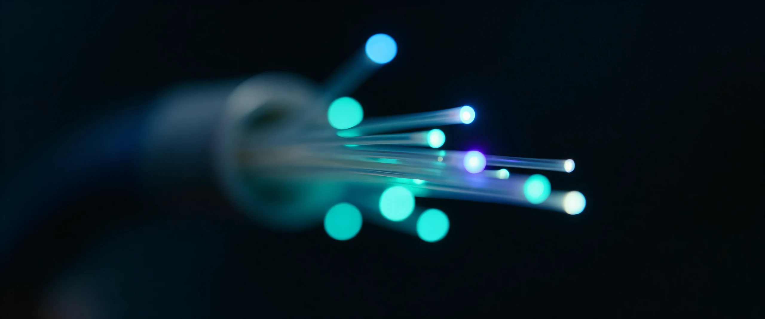 Fibre optic strands glowing blue and teal against black